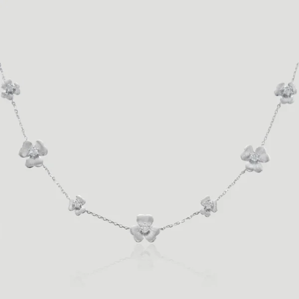 The image showcases a beautifully designed necklace named Bloom | Sterling Silver Flower Necklace. This exquisite piece is crafted from S925 Sterling Silver and adorned with sparkling 5A cubic zirconia stones. The diamond Flower necklace features a series of intricately designed flower-shaped pendants, each resembling a blooming flower with petals encrusted with zirconia, giving them a diamond-like brilliance. The flowers are evenly spaced along a delicate sterling silver chain, creating a harmonious and elegant appearance.