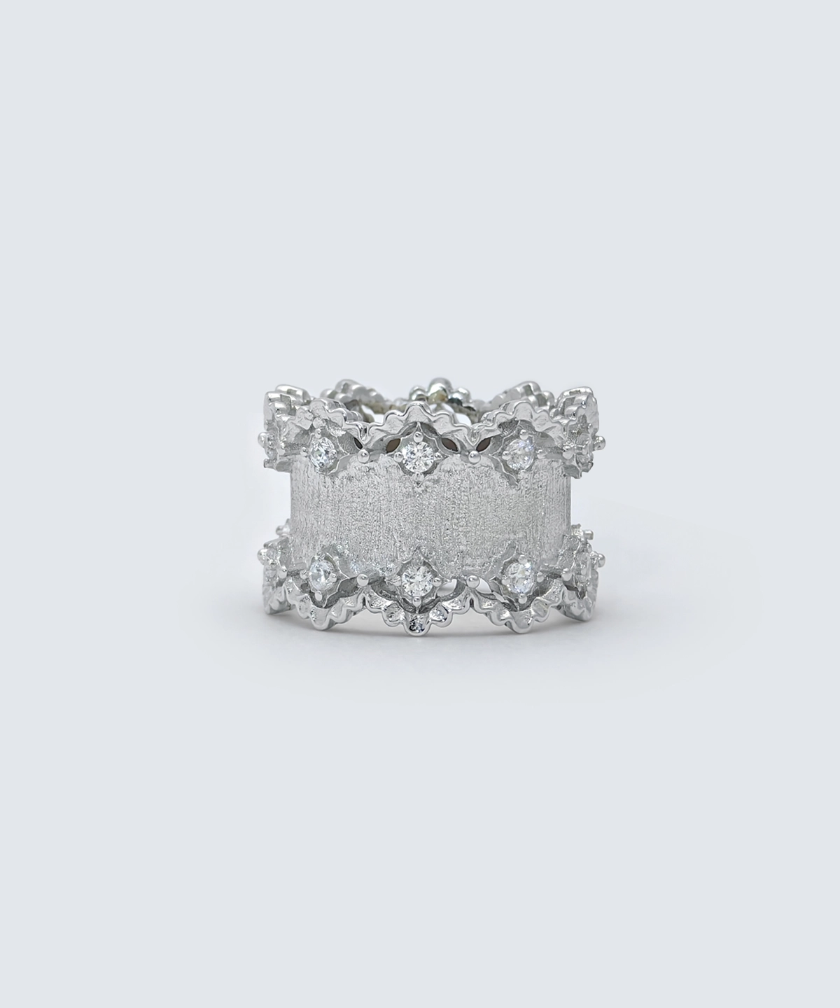 The image shows a beautifully crafted Sterling Silver Lace Edge Ring, named Northern Elegance. The ring features an intricate lace edge design that adds a touch of elegance and sophistication. The surface of the ring has a textured finish, and it is adorned with small, sparkling stones embedded within the lace pattern. This Sterling Silver Ring is an ideal Christmas gift, combining timeless elegance with a unique and detailed design. The reflective surface of the ring enhances its luxurious appearance, making it a standout piece of jewelry.