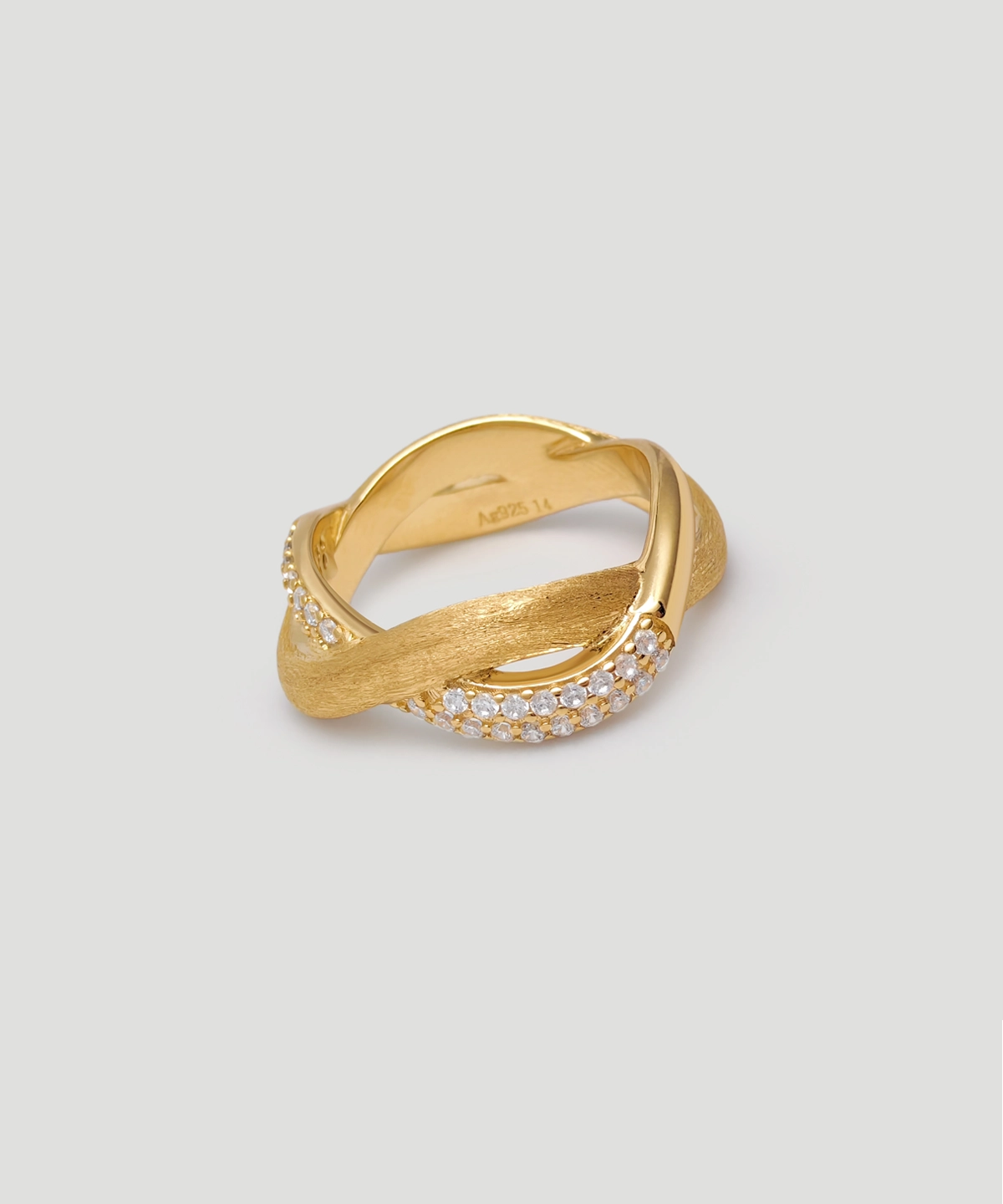 This image shows the "Entwined Dimensions" Intertwined ring, crafted from S925 sterling silver and plated with 18K gold. The ring features a stunning intertwined design, with one part of the band having a smooth, polished finish and the other part adorned with shimmering 5A cubic zirconia stones. The ring is photographed against a clean, light-colored background, and the perspective is slightly tilted to highlight the elegant twist and intricate details of the band. This ring is an exquisite piece of jewelry, perfect for those who appreciate fine craftsmanship and timeless design.