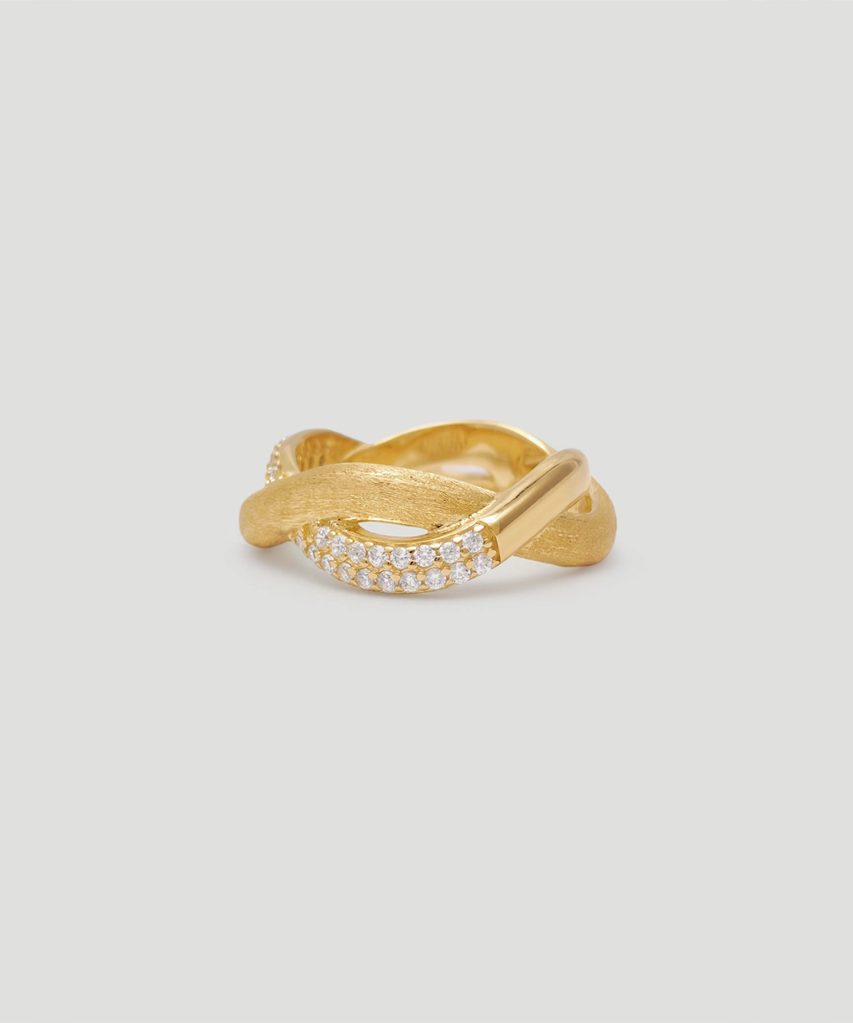 This image shows a beautifully crafted intertwined ring named "Entwined Dimensions." The ring is made of S925 sterling silver and is plated with 18K gold. It features an intertwined design, with one part of the band having a brushed texture and the other part adorned with sparkling 5A cubic zirconia stones. The ring is placed on a plain, light-colored background, and the perspective is slightly angled, showcasing the intricate details and the elegant twist of the band.
