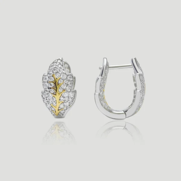 The image shows a pair of Frosted Leaf Sterling Silver Two-Tone Leaf Stud Earrings. These elegant earrings are crafted from S925 sterling silver and adorned with 5A cubic zirconia stones. The design features a two-tone color scheme with a gold-toned leaf vein pattern running through the center of the leaf, surrounded by sparkling 5A zirconia. The earrings are displayed against a plain, light grey background. One earring is shown from the front, highlighting the intricate leaf design and the shimmering stones, while the other earring is displayed from the back, showcasing the clasp mechanism. This presentation emphasizes the detailed craftsmanship and luxurious appearance of the Leaf Stud Earrings, making them visually striking and sophisticated.