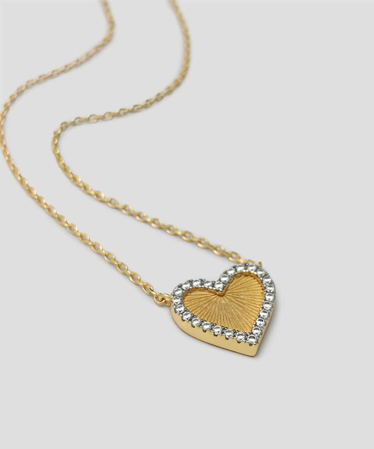 The image showcases a beautifully designed Gold Heart Pendant Necklace. This exquisite piece is crafted from S925 Sterling Silver and plated with 18K gold. The heart-shaped pendant is adorned with sparkling 5A cubic zirconia stones, adding a radiant and elegant touch. The center of the pendant features a textured gold surface, giving it a sunburst effect. The pendant is suspended from a delicate gold chain, also made from S925 Sterling Silver and plated with 18K gold. The necklace is displayed against a light-colored background, highlighting its intricate details and craftsmanship. This description includes the keywords Gold Heart Pendant Necklace and S925 Sterling Silver.