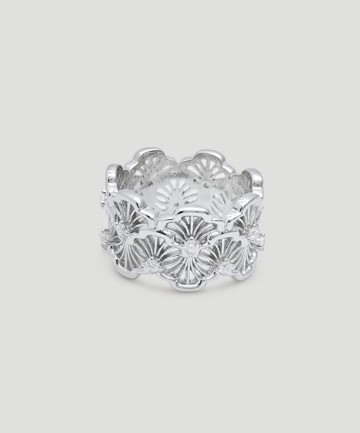 This image showcases a silver lace ring. The ring is made of rhodium-plated sterling silver and is set with 5A cubic zirconia stones. The design of the ring is very intricate, with complex lace patterns engraved on its surface, exuding elegance and sophistication. The ring is circular in shape, and the hollow patterns make it look lighter and more transparent. The ring is placed against a light gray background, with clear details that highlight the ring's shine and delicate textures. The overall design is elegant, suitable for various formal occasions, and is a highly artistic accessory.
