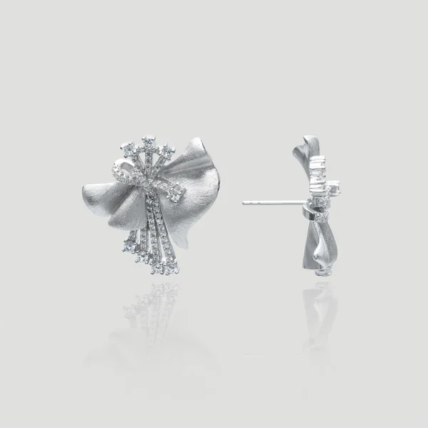 This image shows a pair of large silver bow earrings made from 925 sterling silver. These 925 sterling silver bow earrings feature a radiant ribbon design, combining elegance and brilliance. They are rhodium-plated for extra shine and durability. The earrings are encrusted with sparkling 5A cubic zirconia stones, enhancing their luxurious appeal. Each earring showcases a detailed bow shape with intricate ribbon-like curves, adding a touch of sophistication. The earrings are presented against a plain light grey background, with one earring displayed from the front and the other from a side angle. This presentation highlights the exquisite craftsmanship and intricate detailing of the earrings, making them a stunning piece of jewelry.