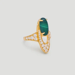 The image features a beautifully designed ring, known as Stardust of the Verdant Wilds. This Malachite ring is crafted from sterling silver plated with 18K gold and showcases an oval-shaped natural malachite stone at its center. Surrounding the malachite are numerous sparkling 5A cubic zirconia stones, enhancing the ring's brilliance and elegance. The ring design includes an elongated, oval shape, with the malachite held securely by four prongs. The gold vermeil setting and the arrangement of the zirconia stones create a luxurious appearance. This Gold Malachite Ring is displayed against a plain, light grey background, which highlights its intricate details and craftsmanship.