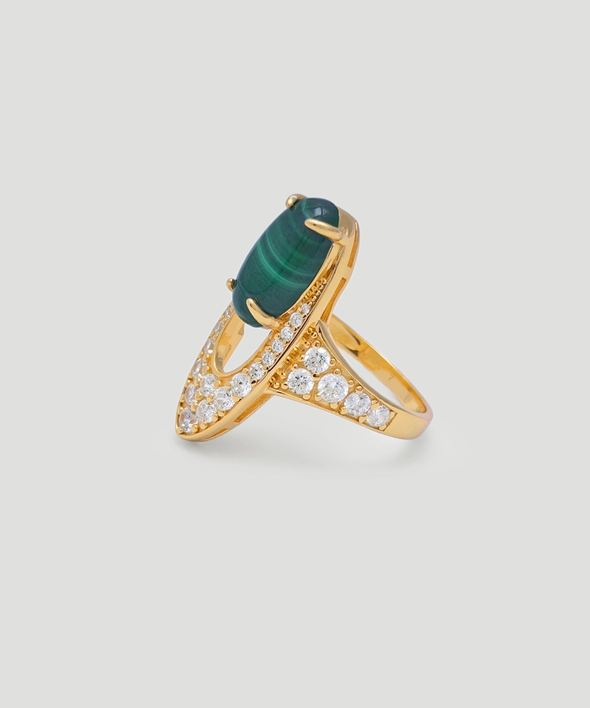 The image features an exquisite Gold Malachite Ring, crafted from S925 sterling silver plated with 18K gold. The centerpiece of this stunning piece is an oval-shaped natural malachite stone, securely held by four prongs. Surrounding the malachite are numerous sparkling 5A cubic zirconia stones, enhancing the ring's brilliance and elegance. The ring is displayed from a side view, showcasing its intricate design and craftsmanship.