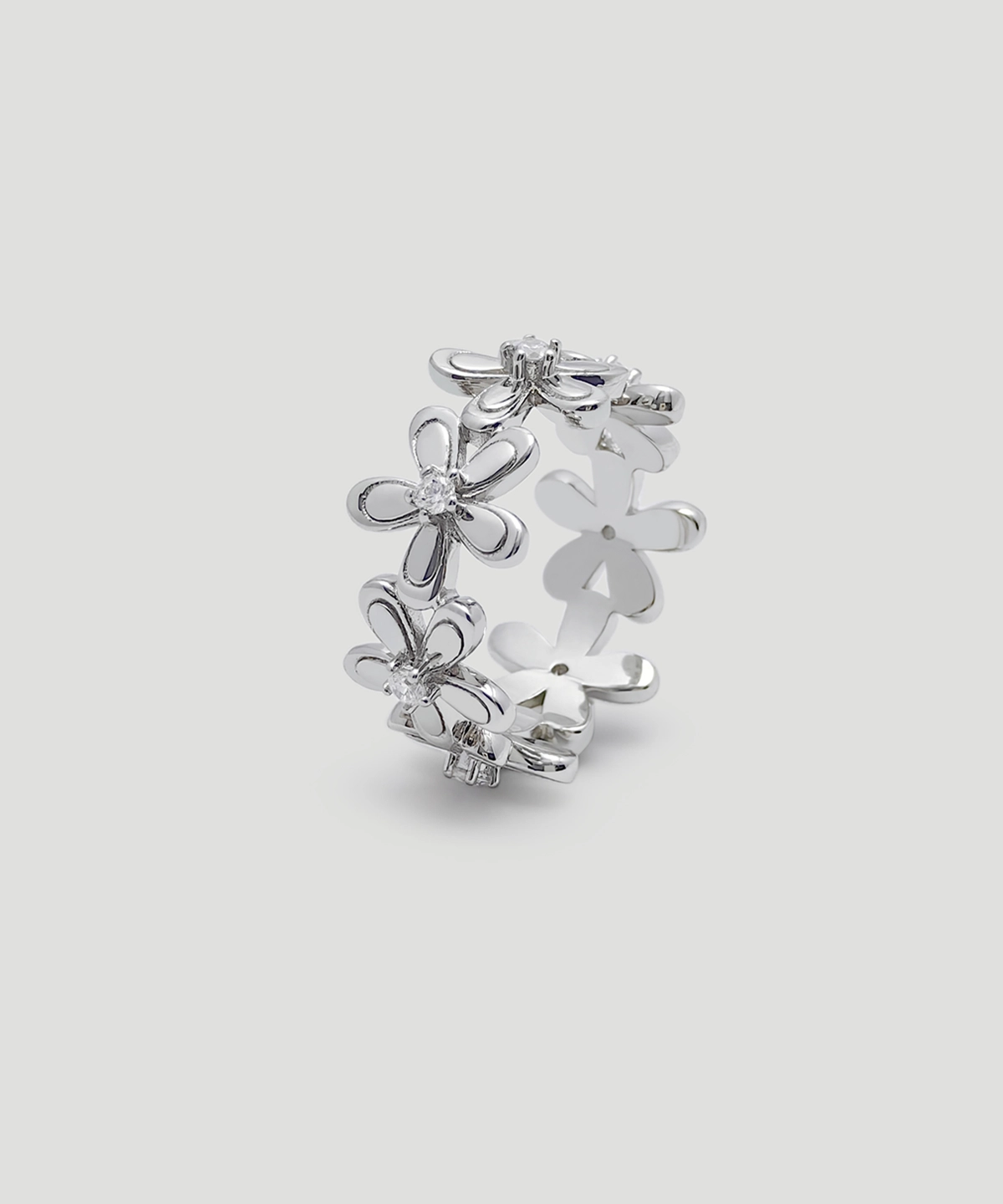 This image is the "Sunshine | Sterling Silver flower Ring." The picture showcases a beautifully crafted ring standing upright, perfectly displaying the ring's shape. The main body of the ring is designed in the shape of flowers, with each flower made of sterling silver. The arrangement of the flowers makes the entire ring look like a blooming floral wreath and is studded with 5A-grade zirconia. The surface of the ring is smooth, and the silver sheen gives it a very refined and elegant appearance.