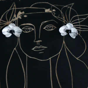 Butterfly Orchid Earrings | 925 Sterling Silver Floral Studs — Displayed on an artistic black canvas with a delicate line-drawn female portrait, these handcrafted earrings resemble blooming orchid petals with intricate textures and a bold black center. The floral studs are placed at the eyes of the portrait, creating a striking visual metaphor. Designed for modern women who appreciate artistic, nature-inspired jewelry with a statement touch. Ideal for gifting or everyday elegance.
