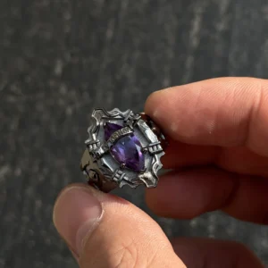 The image showcases a stunning sterling silver ring inspired by the anime Katekyo Hitman Reborn! This piece of Handmade Anime Jewelry is meticulously designed as Kyoya Hibari’s Vongola Cloud Ring. The ring features sharp, angular patterns that give it a bold and gothic look. At its center is a brilliant natural amethyst gemstone, radiating a deep purple hue that symbolizes the Cloud Flame’s power and elegance. The polished sterling silver band perfectly complements the gemstone’s vibrant color. Above the gemstone, the word "VONGOLA" is engraved, emphasizing its connection to the anime and its significance as a Katekyo Hitman Reborn Ring. The ring’s intricate craftsmanship and attention to detail make it an exceptional piece for fans and collectors of Vongola Rings.
