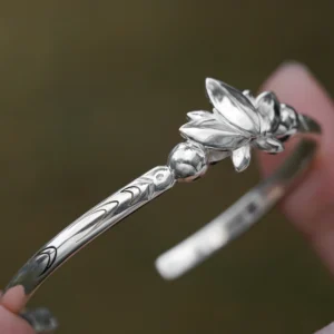 The Lazesoul Handmade Anime Jewelry — 999 Pure Silver Open Adjustable Bangle, inspired by Frieren: Beyond Journey's End, embodies elegance and artistry. The bracelet features a sculpted lotus motif, symbolizing wisdom and renewal, with intricate engravings accentuating its refined craftsmanship. Designed for anime collectors and jewelry enthusiasts, its adjustable open design ensures a comfortable fit. Set against a soft-focus backdrop, the image highlights the bangle’s polished texture, emphasizing its premium quality. Ideal for cosplay or daily wear, this anime-inspired luxury accessory adds sophistication to any look.