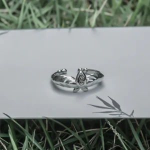 The Mirror Lotus Ring from Lazesoul Handmade Anime Jewelry is a 999 pure silver adjustable ring, inspired by Frieren: Beyond Journey’s End. The image showcases the ring placed on a reflective surface, surrounded by green grass, creating a serene and nature-inspired setting. The intricate lotus motif and mirror-like finish highlight its craftsmanship, making it an ideal choice for anime collectors and jewelry enthusiasts. The open-band design ensures versatile sizing, while the high-quality silver enhances its luminous appeal. A timeless fantasy-inspired accessory, perfect for daily wear or special occasions.