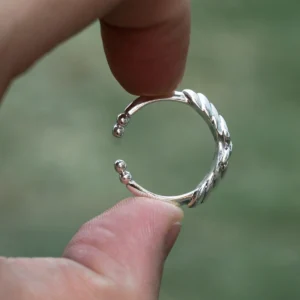The Mirror Lotus Ring from Lazesoul Handmade Anime Jewelry is a 999 pure silver adjustable ring inspired by Frieren: Beyond Journey's End. Featuring intricate lotus patterns, its open-band design ensures a comfortable fit, with delicate silver ball accents at each end. The high-polish finish enhances its elegance, making it a refined piece for anime collectors and jewelry enthusiasts alike. In the image, the ring is delicately held between two fingers, with a soft green blurred background that accentuates its artistry. A perfect fusion of fantasy and craftsmanship, ideal for daily wear or special occasions.