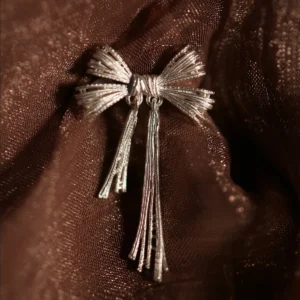Product image of our 925 Sterling Silver Bow Ear Cuff | No Piercing Earrings displayed against a rich, textured brown fabric. The ear cuff features an elegant bow design with intricate detailing and a polished, luminous finish, embodying modern sophistication and timeless style. Ideal for trendsetters seeking stylish, non-piercing ear jewelry, this premium accessory highlights superior craftsmanship and adds a refined accent to any look.