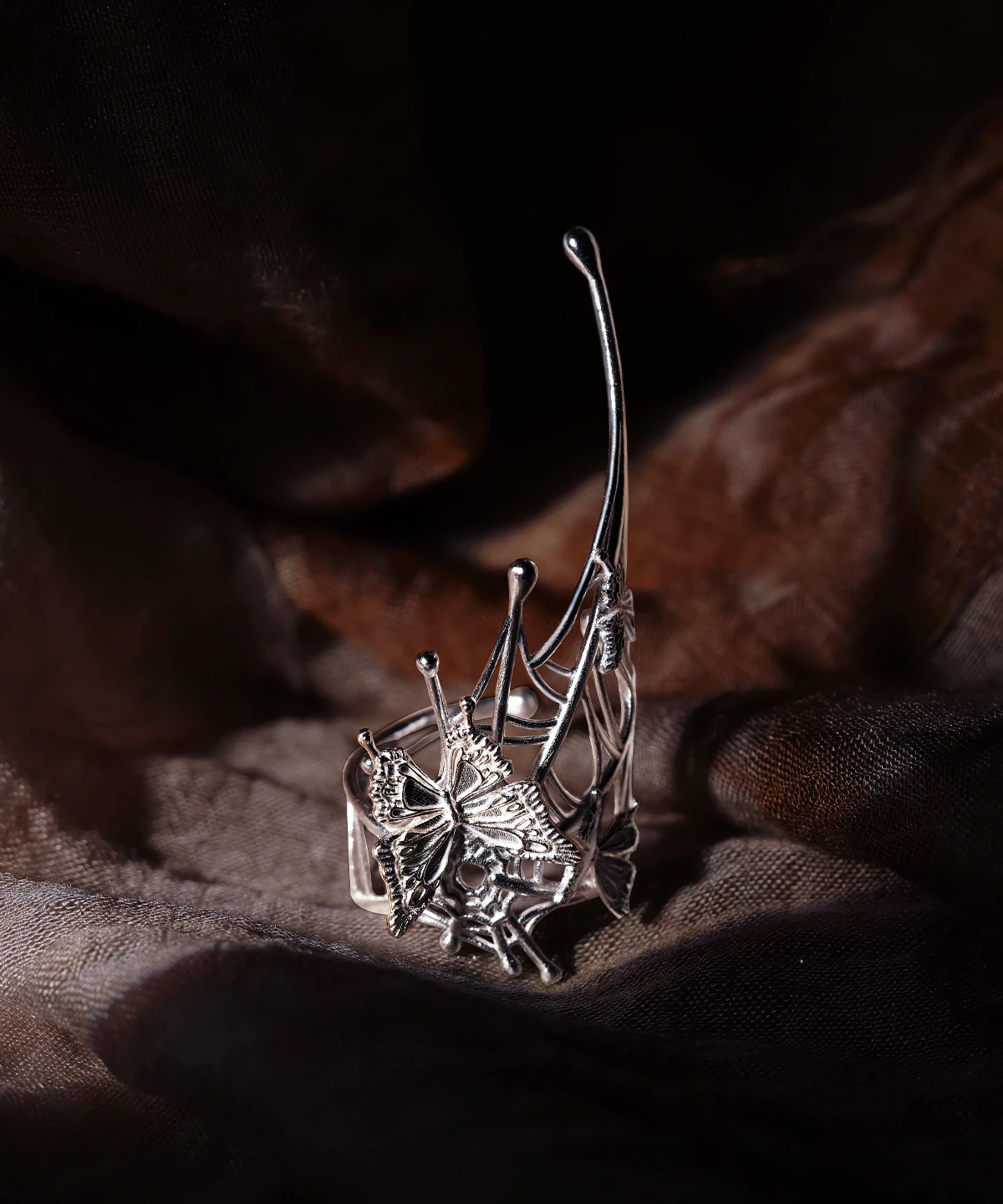 Butterfly Ring in 925 Sterling Silver | Art Fantasy Pinky Ring showcases an intricately crafted silver band with a detailed butterfly and delicate web-like accents. Set against a dark, textured backdrop that emphasizes its luminous finish, this unique accessory exudes modern elegance and whimsical artistry. Perfect for trendsetters, this statement pinky ring blends fantasy inspiration with refined craftsmanship, making it ideal for both casual and formal wear.