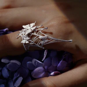 Butterfly Ring in 925 Sterling Silver | Art Fantasy Pinky Ring features an intricate spider web design adorned with delicate butterflies. Displayed on a model’s hand against a vibrant backdrop of purple blooms, this statement piece combines whimsical artistry with refined craftsmanship. Perfect for trendsetters and fashion enthusiasts, it brings a unique, fantasy-inspired touch to both casual and formal styles.