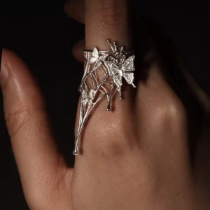 Close-up image of a hand wearing our Butterfly Ring in 925 Sterling Silver | Art Fantasy Pinky Ring. Featuring an intricate, web-inspired design adorned with delicate butterfly motifs, this ring highlights exceptional craftsmanship. The model's hand is set against a dark, textured backdrop, emphasizing the ring’s artistic detail and bold allure. Perfect for fashion-forward trendsetters seeking whimsical, statement jewelry, this unique pinky ring seamlessly blends modern elegance with fantasy-inspired design.