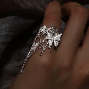 Butterfly Ring in 925 Sterling Silver | Art Fantasy Pinky Ring features an intricately designed silver band adorned with delicate butterfly motifs and a subtle web-inspired pattern. Captured in a close-up on a model’s hand against a dark, textured backdrop, the ring’s shimmering details stand out beautifully. This whimsical yet elegant piece exudes refined craftsmanship, making it a perfect statement accessory for both casual and formal wear, ideal for fashion-forward trendsetters.