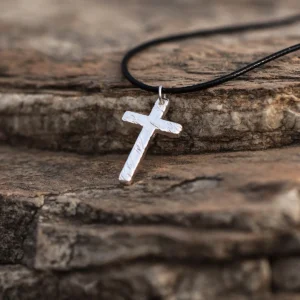 Handcrafted from pure 999 silver, this cross pendant features a textured, rustic finish that enhances its artisanal charm. Suspended from a sleek black cord, the design balances elegance with understated simplicity. The silver’s subtle shine contrasts against the dark, stone-like backdrop, highlighting its refined craftsmanship. Perfect for those seeking a timeless yet distinct accessory.