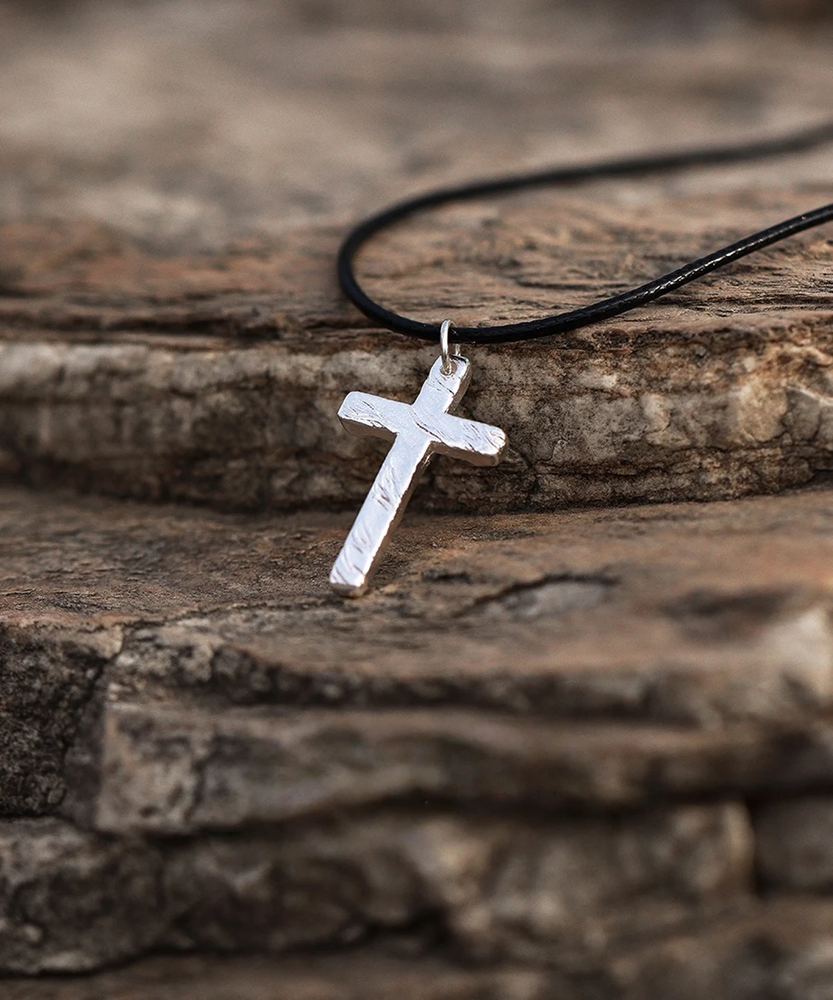 Handcrafted from pure 999 silver, this cross pendant features a textured, rustic finish that enhances its artisanal charm. Suspended from a sleek black cord, the design balances elegance with understated simplicity. The silver’s subtle shine contrasts against the dark, stone-like backdrop, highlighting its refined craftsmanship. Perfect for those seeking a timeless yet distinct accessory.