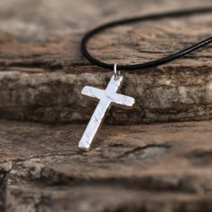 Handcrafted from pure 999 silver, this cross pendant features a textured, rustic finish that enhances its artisanal charm. Suspended from a sleek black cord, the design balances elegance with understated simplicity. The silver’s subtle shine contrasts against the dark, stone-like backdrop, highlighting its refined craftsmanship. Perfect for those seeking a timeless yet distinct accessory.