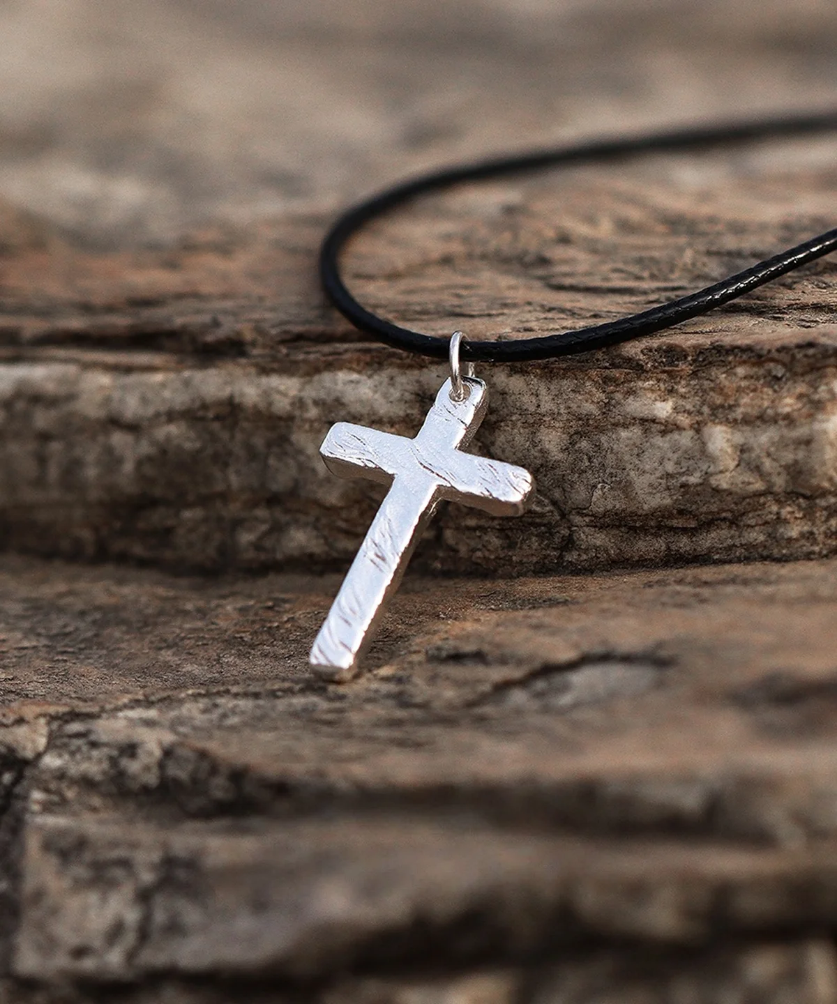 Handcrafted from pure 999 silver, this cross pendant features a textured, rustic finish that enhances its artisanal charm. Suspended from a sleek black cord, the design balances elegance with understated simplicity. The silver’s subtle shine contrasts against the dark, stone-like backdrop, highlighting its refined craftsmanship. Perfect for those seeking a timeless yet distinct accessory.