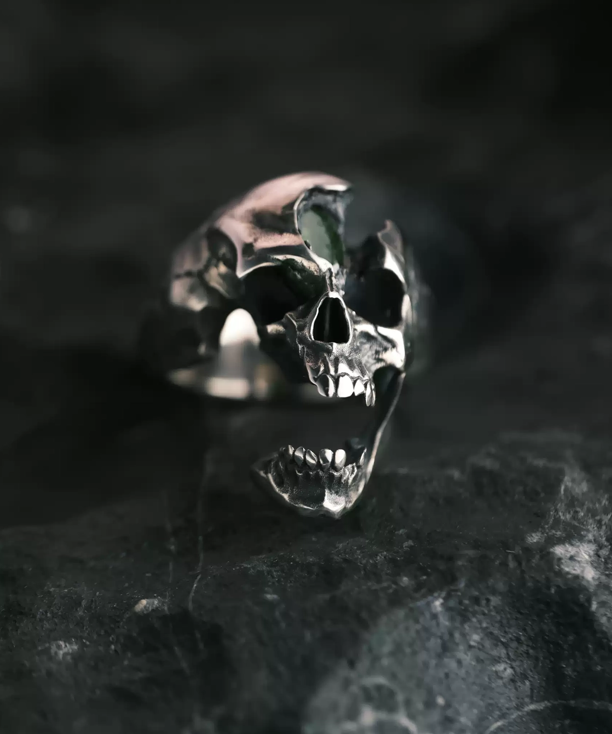 A close-up of the Dark Skull Ring crafted from S925 silver, featuring an intricately detailed skull design with an open jaw and a gemstone inlay. The ring's bold, dark aesthetic enhances its edgy appeal, making it a striking accessory.