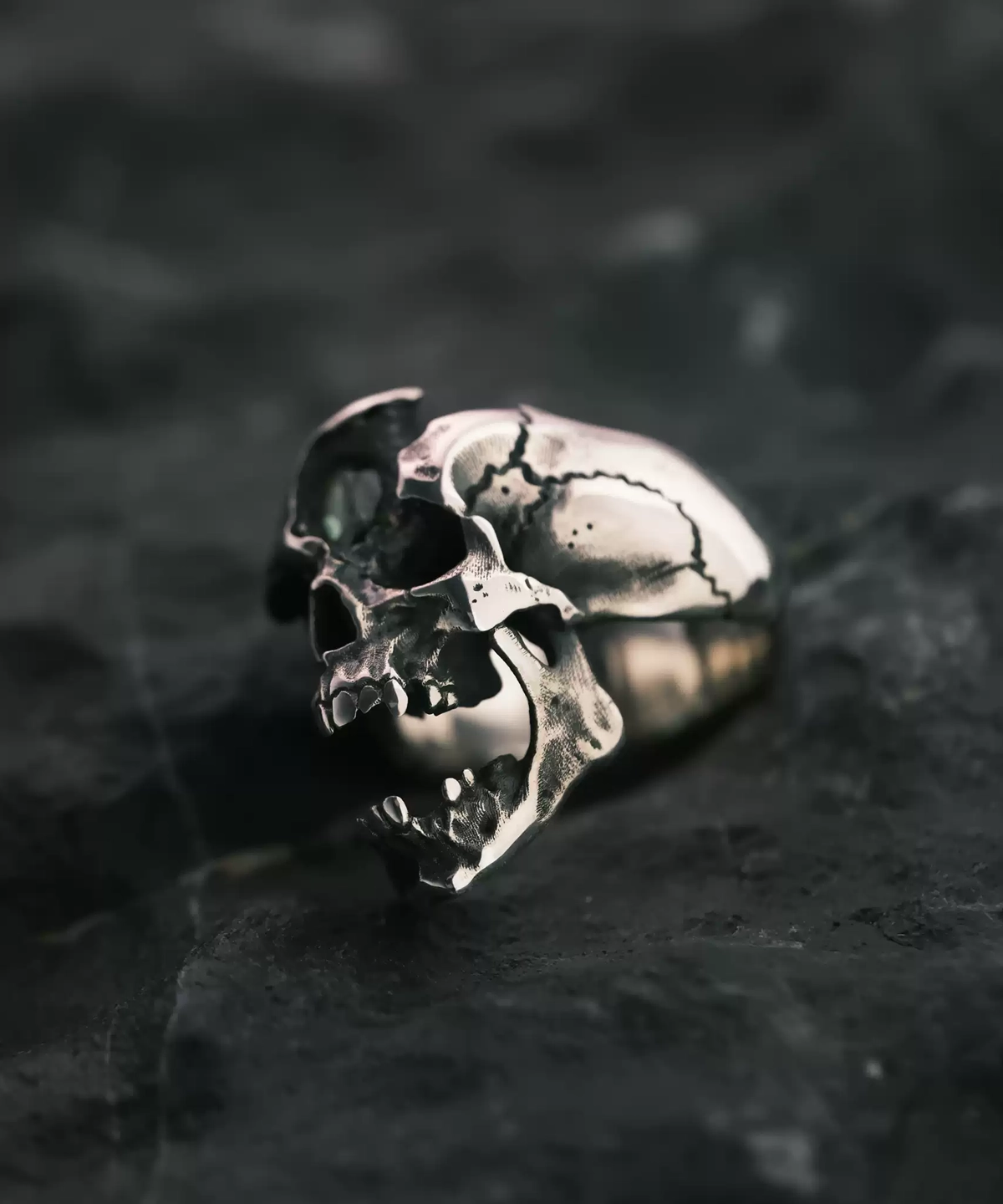Dark Skull Ring – S925 Silver with Gemstone Inlay, featuring an intricately carved skull motif with deep, shadowed contours. The skull sits atop a textured silver band, enhanced by a gemstone inlay that adds a mysterious, gothic elegance. The high-contrast design highlights the ring’s bold, rebellious aesthetic, making it a standout piece for lovers of statement jewelry.