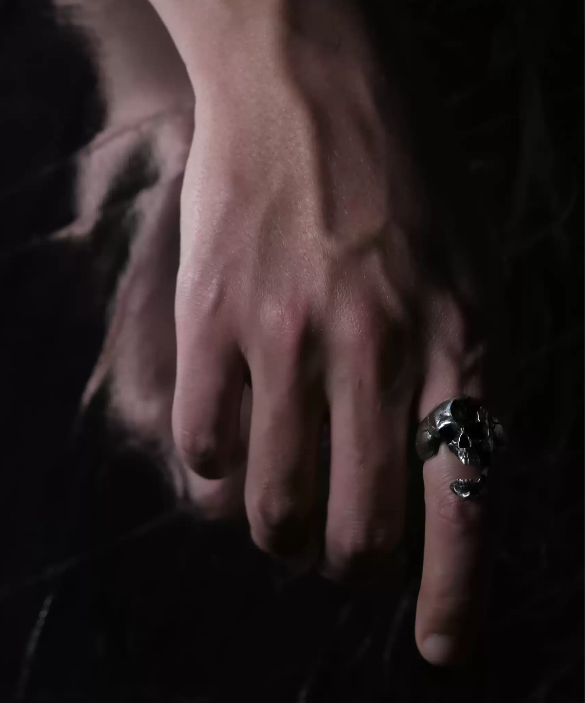 A close-up of a hand wearing the Dark Skull Ring – S925 Silver with Gemstone Inlay. The ring showcases an intricately carved skull motif, accented with a gemstone inlay for a bold, gothic aesthetic.
