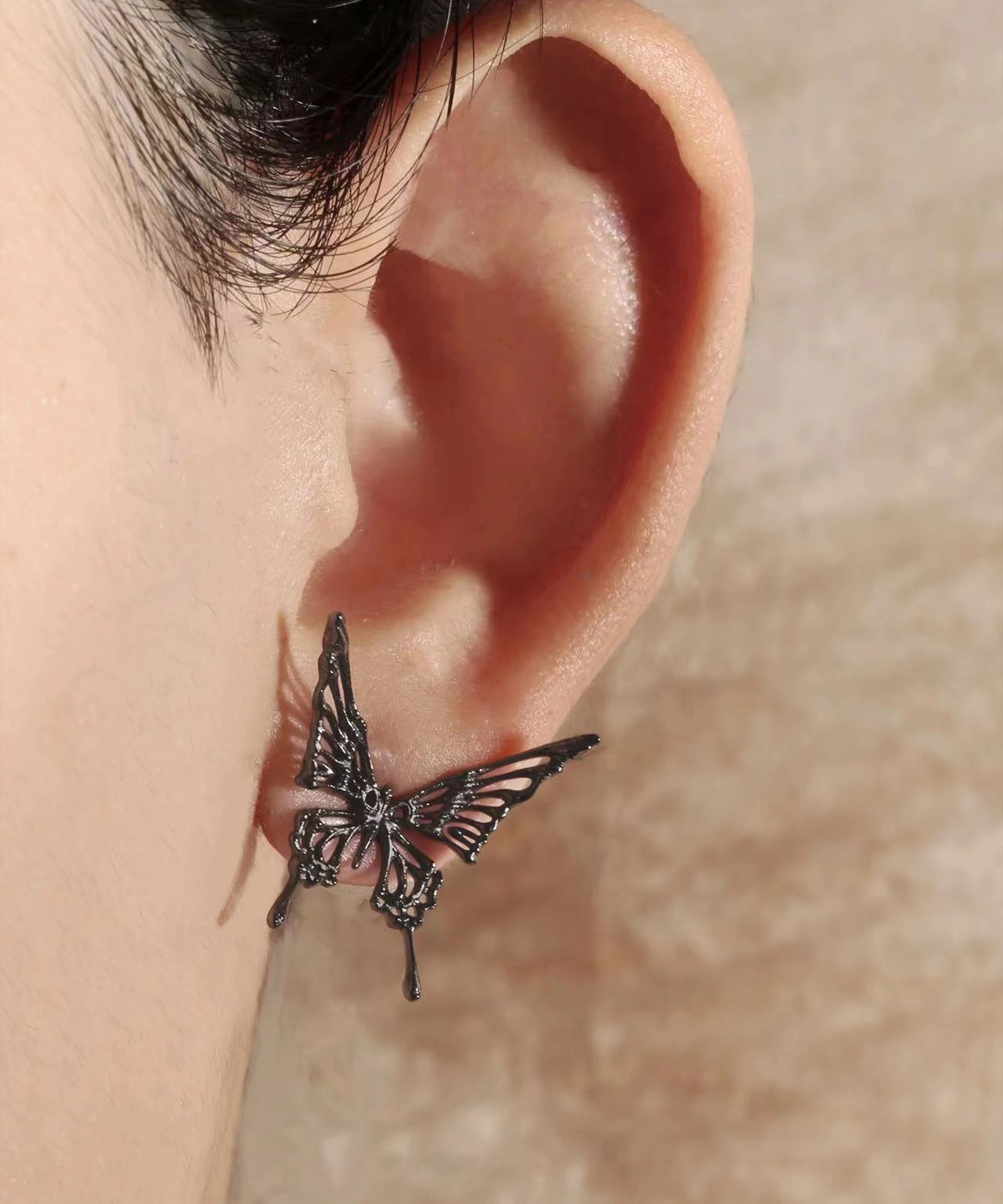 Close-up image of a person's ear wearing Dream Butterfly Earrings & Ear Cuffs. The earring is designed as a delicate butterfly, with intricate details and no piercing needed. The model is showcasing the stud version of the butterfly earrings.