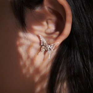This image captures a detailed close-up of Dream Butterfly Stud Earrings, delicately positioned on the ear. The jewelry showcases an elegant butterfly motif, intricately crafted to highlight its artistic finesse. The soft lighting in the image enhances the delicate details, casting gentle shadows that add dimension to the butterfly earrings. Perfect for those seeking ethereal, nature-inspired jewelry with a seamless and adjustable fit.