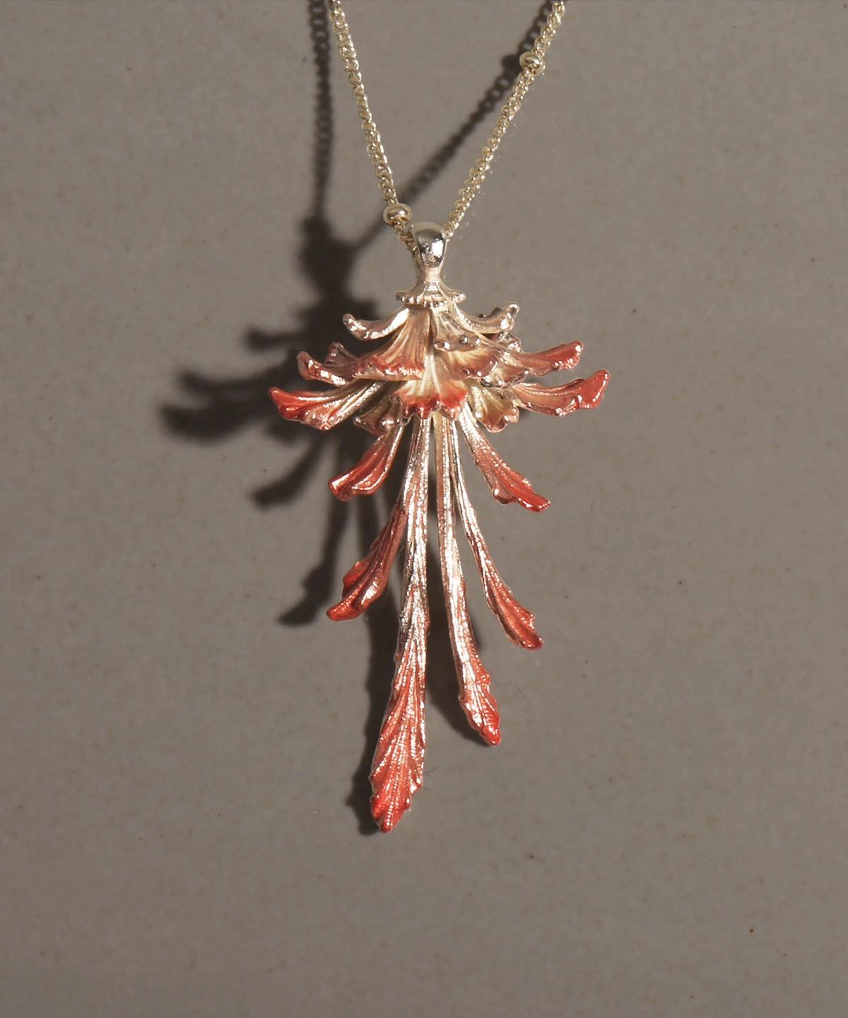 Drooping Blossom | 925 Sterling Silver Long Necklace features a stunning floral pendant with cascading, elongated petals that shift from a luminous metallic silver to rich reddish-orange tips. Suspended from a sleek sterling silver chain and set against a dark, textured backdrop, this statement piece exudes refined elegance and modern sophistication. Ideal for both formal occasions and everyday wear, it highlights exceptional craftsmanship and timeless allure.