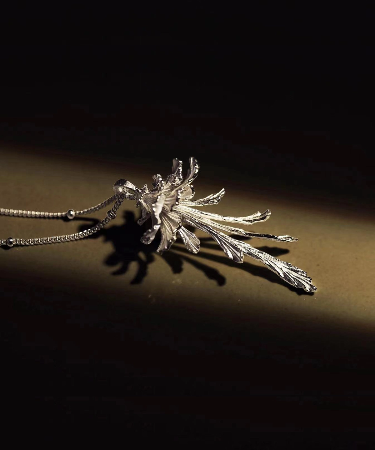 Drooping Blossom | 925 Sterling Silver Long Necklace features an intricately designed floral pendant with elongated petals, suspended on a delicate chain of small round links. The elegant silver tone contrasts beautifully against a dark, textured backdrop, highlighting its refined craftsmanship. Perfect for both casual and formal wear, this necklace exudes timeless sophistication and artisanal luxury.