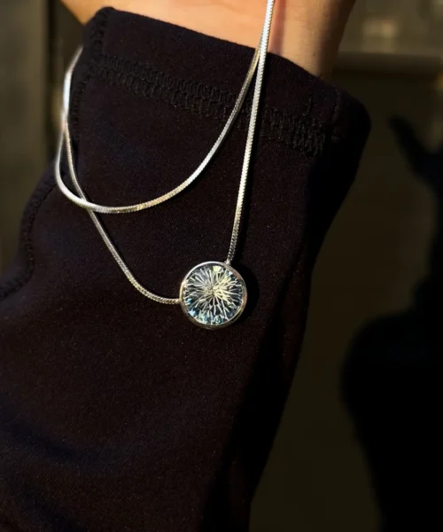 A sterling silver blue eyes necklace, inspired by Gojo Satoru’s Six Eyes. The round pendant features an intricate, starburst-like design with a luminous natural topaz at its center, evoking the brilliance of his signature gaze. Its reflective silver details contrast elegantly against a dark backdrop, enhancing the gemstone’s glow—a perfect fusion of anime symbolism and fine craftsmanship.