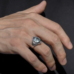 A close-up of a hand adorned with the Six Eyes Ring in Sterling Silver, featuring a striking natural topaz. The intricate craftsmanship and luminous gemstone contrast against a dark background, enhancing its brilliance.