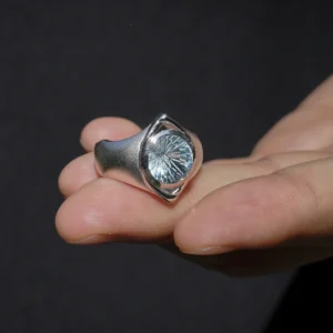 Six Eyes Ring in Sterling Silver with Natural Topaz, resting elegantly on an open palm against a dark backdrop, highlighting its intricate craftsmanship.