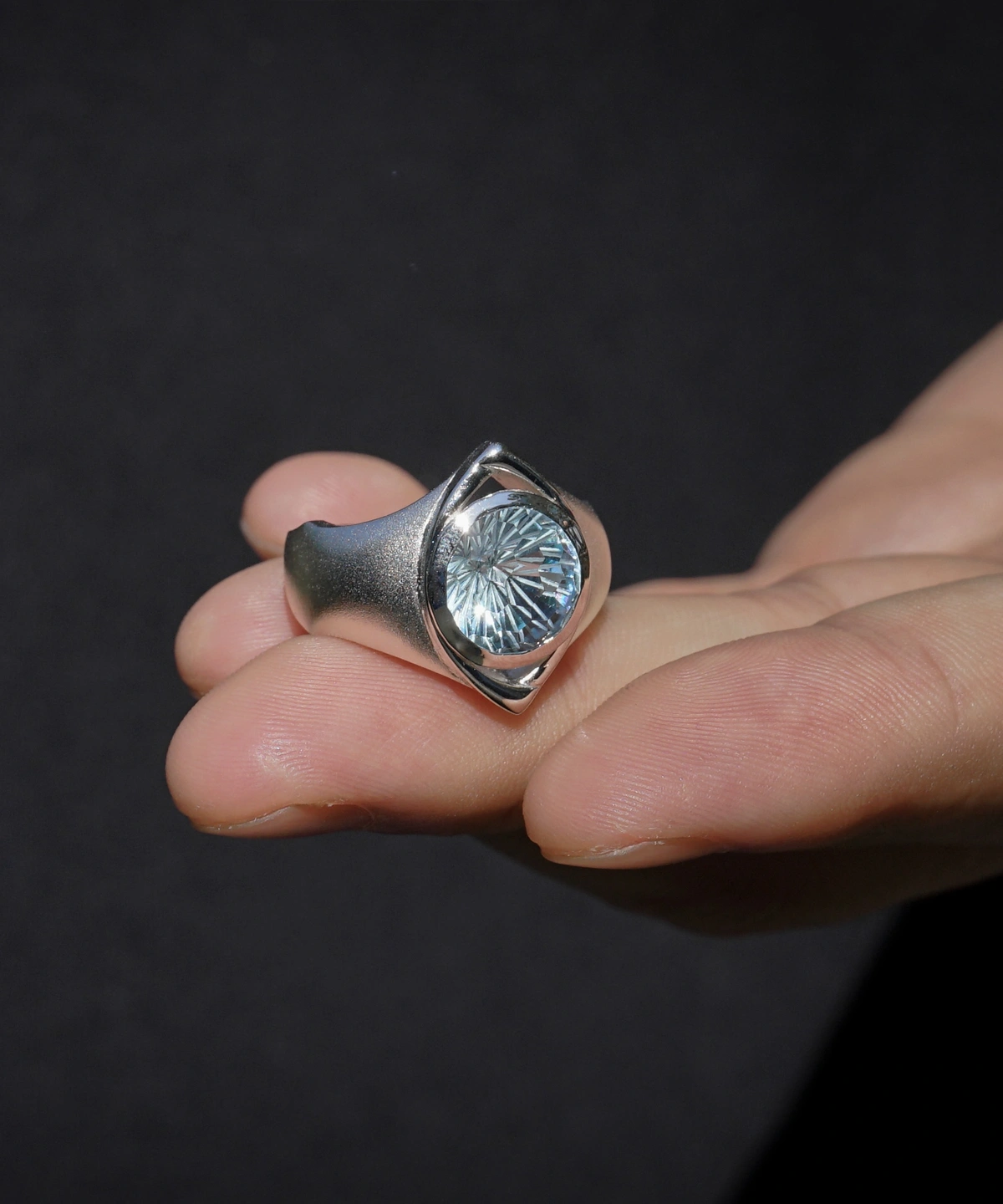 Six Eyes Ring in Sterling Silver with Natural Topaz, resting elegantly on an open palm against a dark backdrop, highlighting its intricate craftsmanship.