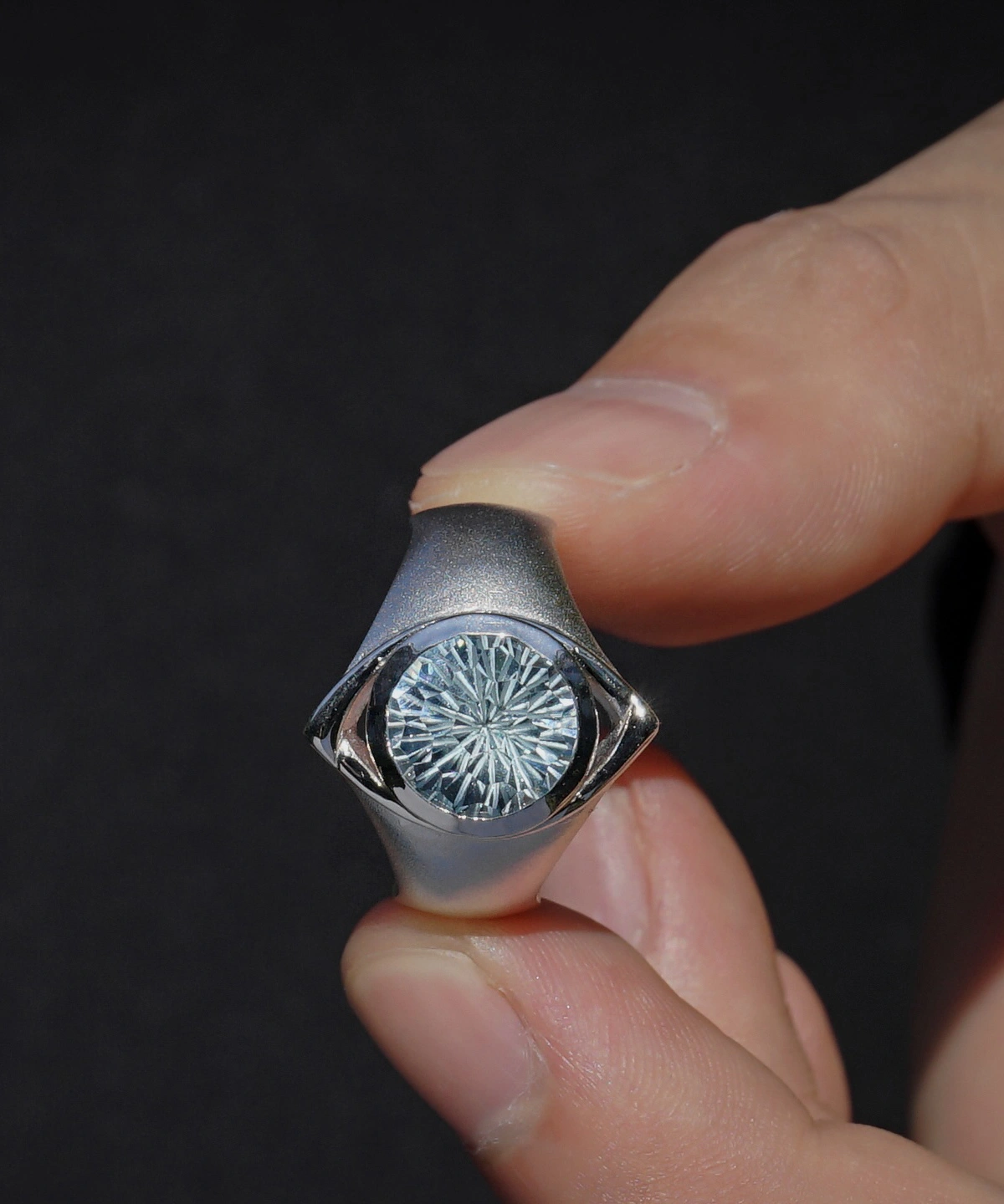 Six Eyes Ring in Sterling Silver with Natural Topaz, resting elegantly on an open palm against a dark backdrop, highlighting its intricate craftsmanship.