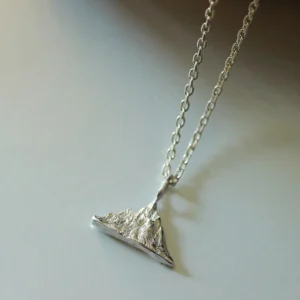 A close-up view of the Snow Mountain Necklace, featuring a 999 Pure Silver Pendant designed to resemble a majestic snow-capped mountain range. The finely crafted silver pendant hangs elegantly from a delicate silver chain.