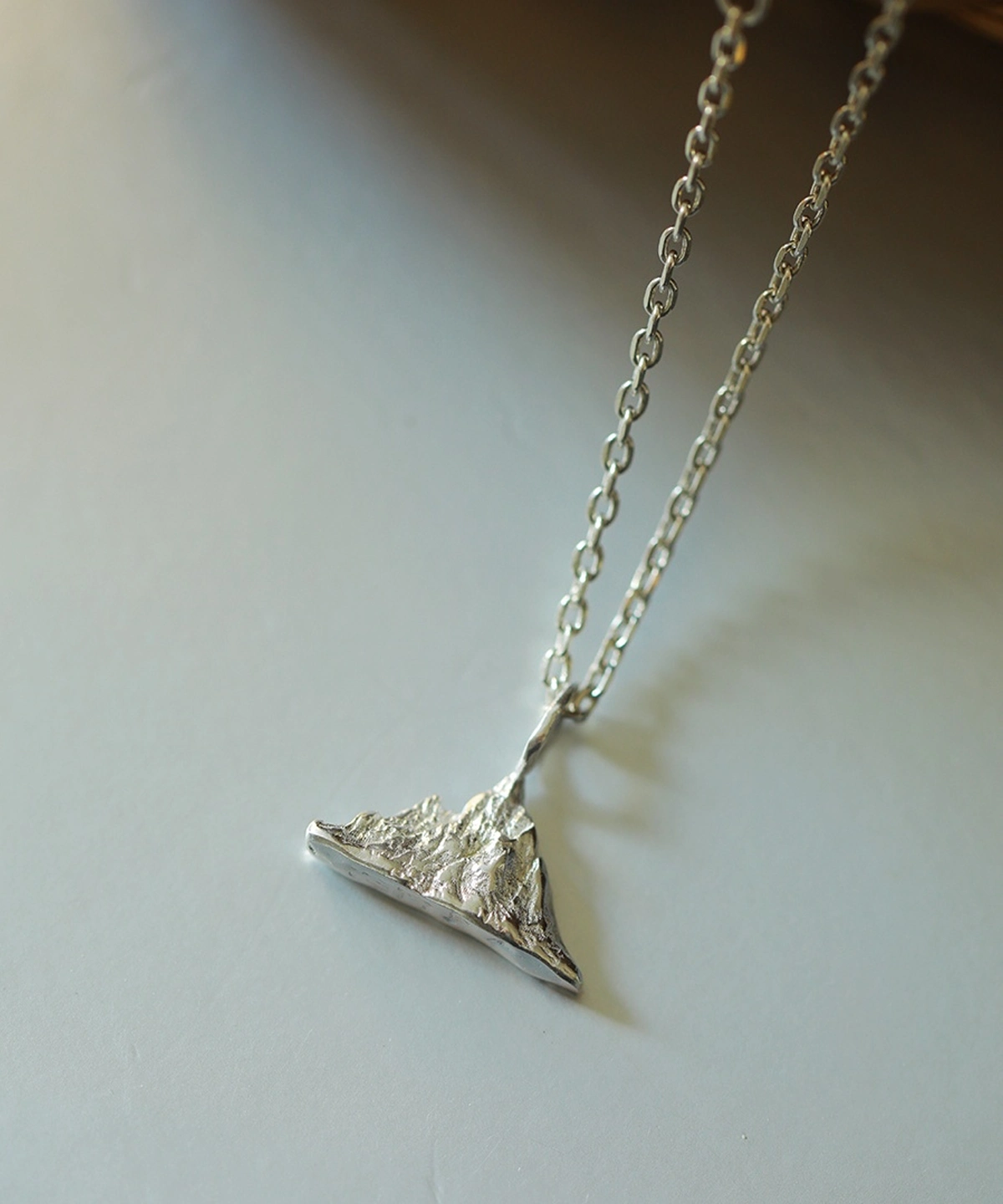 A close-up view of the Snow Mountain Necklace, featuring a 999 Pure Silver Pendant designed to resemble a majestic snow-capped mountain range. The finely crafted silver pendant hangs elegantly from a delicate silver chain.
