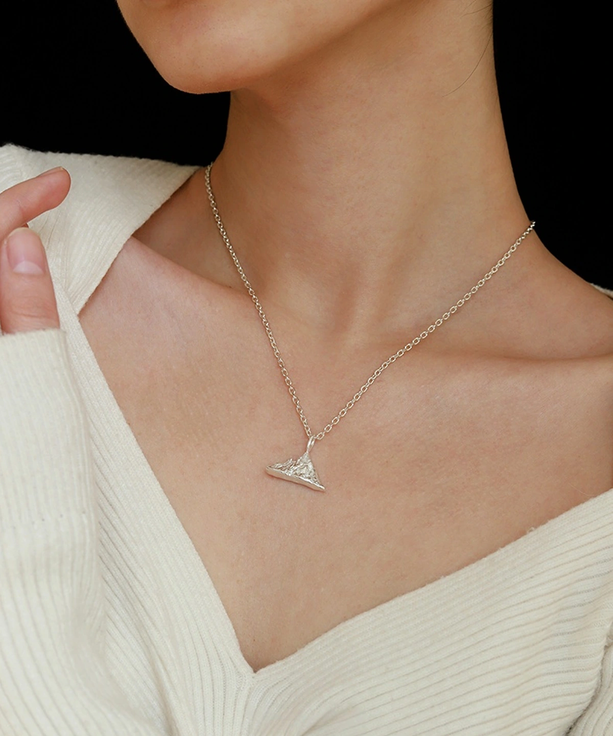 A person wearing the Snow Mountain Necklace with a 999 Pure Silver Pendant, featuring a triangular, snow-capped mountain design. The fine silver chain complements the pendant’s elegant craftsmanship. The person is dressed in a light-colored, textured top, providing a subtle background to highlight the necklace’s details.