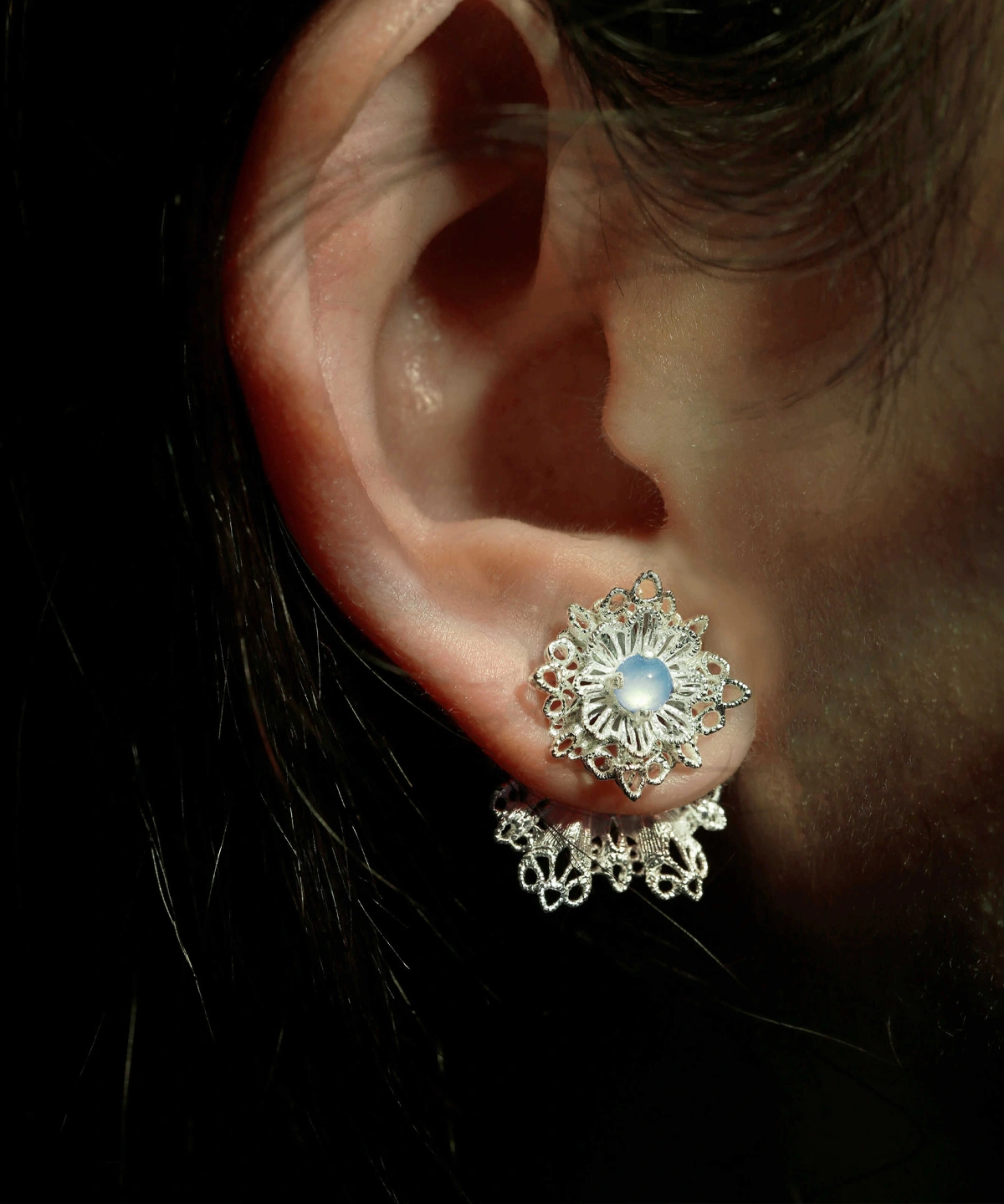 A close-up of an ear wearing Snowflake Earrings—delicate 925 Sterling Silver Lace Stud Earrings with an intricate snowflake-inspired filigree design and a central pearl-like bead.