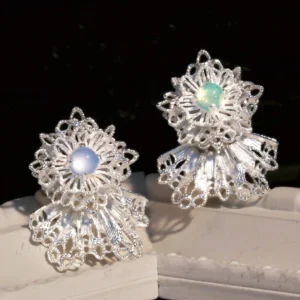 These Snowflake Earrings embody delicate artistry and winter-inspired elegance. Crafted from 925 sterling silver, each earring features an intricate lace-like snowflake design, capturing the beauty of frost-kissed patterns. At the heart of each piece sits a shimmering gemstone—one in a serene blue hue and the other in a soft green—adding a subtle yet mesmerizing touch of color. The silver framework reflects light gracefully, enhancing its refined allure. Displayed against a contrasting dark background, these earrings exude sophistication, making them a perfect blend of seasonal charm and timeless craftsmanship.