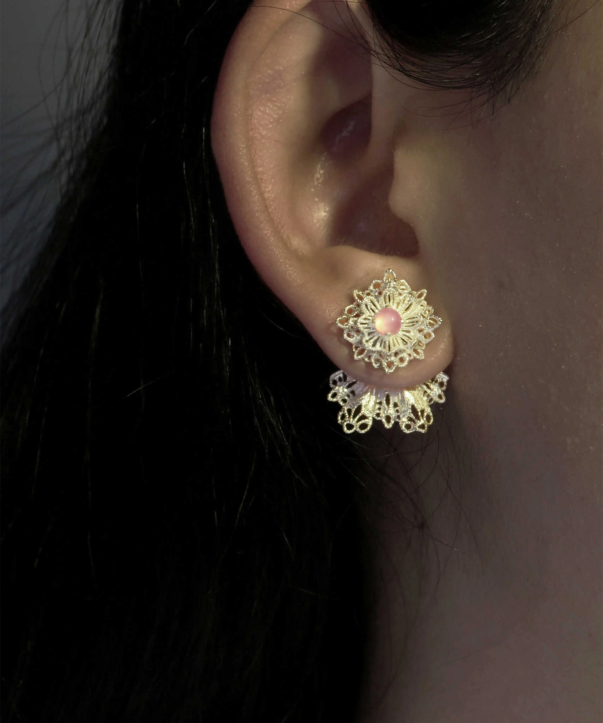 A close-up image of an ear wearing Snowflake Earrings. The earrings are 925 Sterling Silver Lace Stud Earrings, featuring a delicate snowflake design with a pink center stone and intricate lace-like details hanging below.