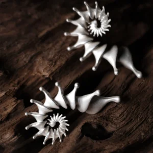 A pair of Spiral Earrings crafted from S925 Sterling Silver, designed as ear cuffs with a unique spiral structure. The earrings feature smooth, flowing curves with tapered ends, resembling abstract organic forms. Their polished silver finish enhances their modern, artistic appeal. Displayed on a textured wooden surface, the intricate craftsmanship and elegant aesthetic of these Designer Ear Cuffs are emphasized.