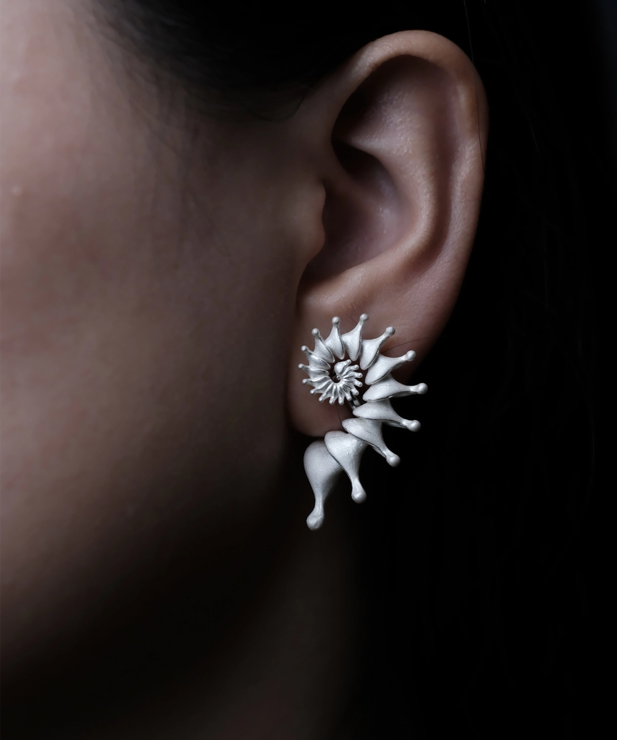 Close-up of a woman's left ear adorned with a Spiral Earrings piece—a Designer Ear Cuff crafted from S925 Sterling Silver. The ear cuff elegantly wraps around the ear’s curve, showcasing its refined spiral shape and pointed accents.