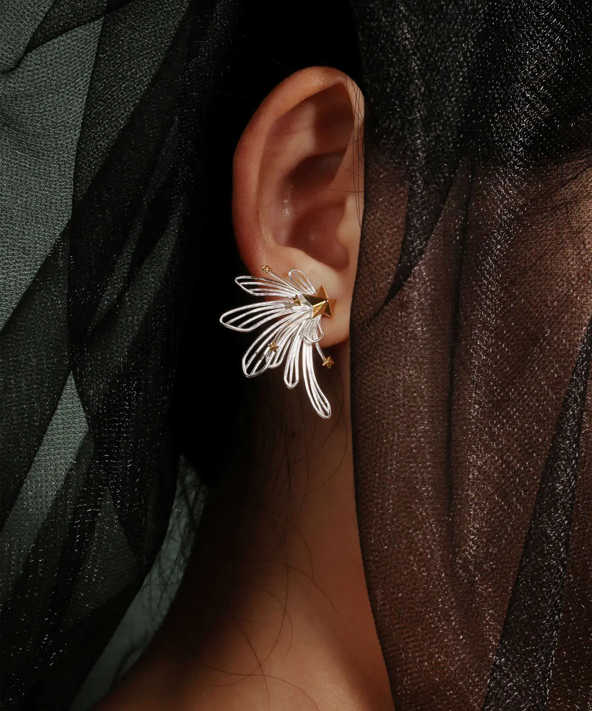A close-up of an ear showcases the Star Trail | 925 Sterling Silver Star Ear Cuffs, elegantly wrapped around the outer edge. The design features delicate silver stars arranged in a celestial pattern, creating a sophisticated and airy look. The cuff is lightweight and comfortable, seamlessly blending modern artistry with timeless elegance. Its polished sterling silver finish catches the light beautifully, making it a standout piece for any occasion.