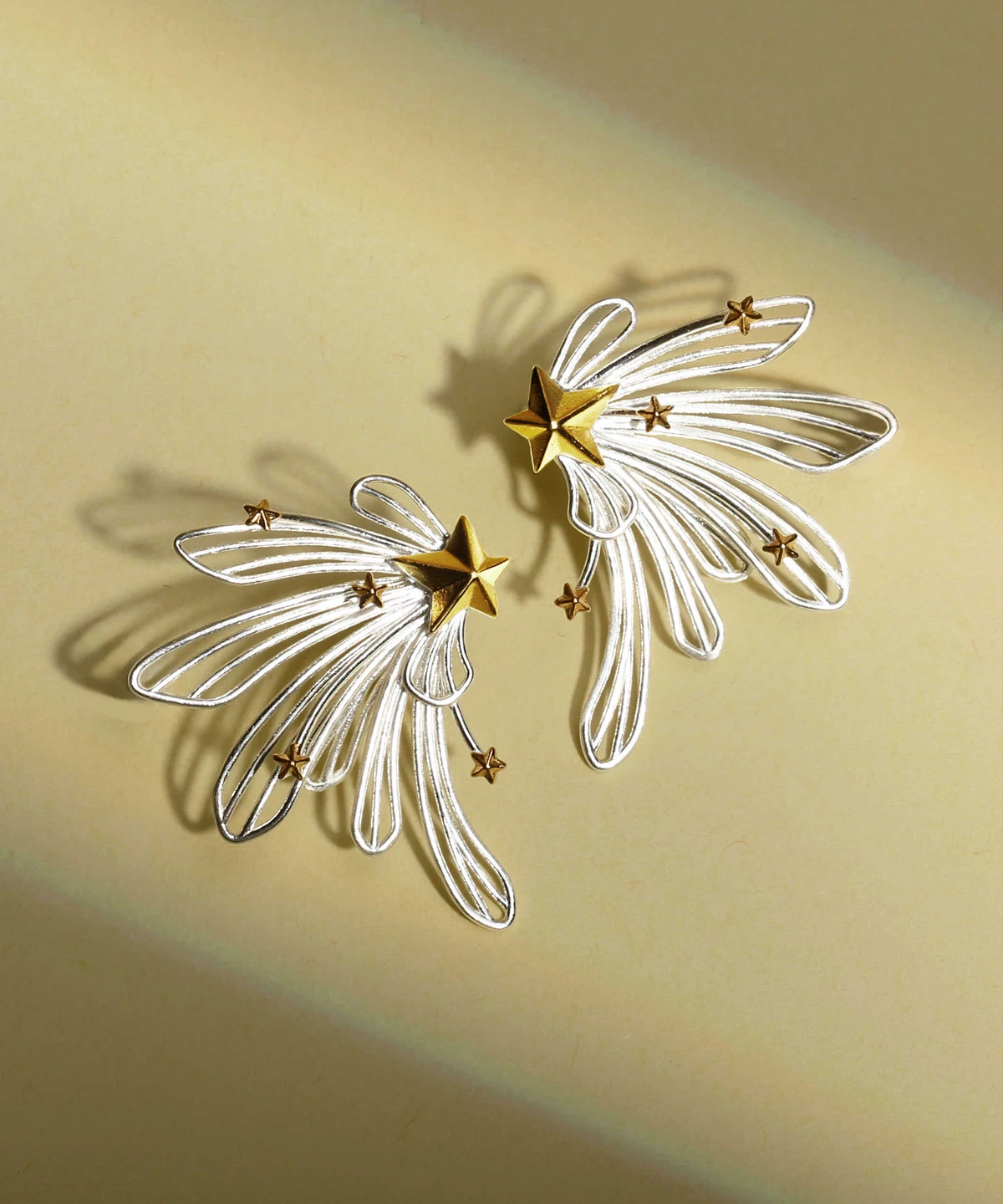 A celestial-inspired jewelry piece, the Star Trail | 925 Sterling Silver Star Stud Earrings & Ear Cuffs feature a striking gold star with delicate silver trails, creating the illusion of a shooting star. Adorned with smaller gold stars along its elegant arc, this design beautifully hugs the ear. The close-up image captures its intricate craftsmanship, with a gently touching hand adding a graceful touch. Made with 925 sterling silver, this accessory blends sophistication with a dreamy cosmic allure. Perfect for those who love starry elegance.