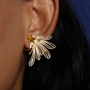 A close-up of a woman's ear showcases the Star Trail 925 Sterling Silver Star Stud Earrings, featuring delicate silver loops and gold star accents radiating from a central gold star. The design evokes the motion of a shooting star.