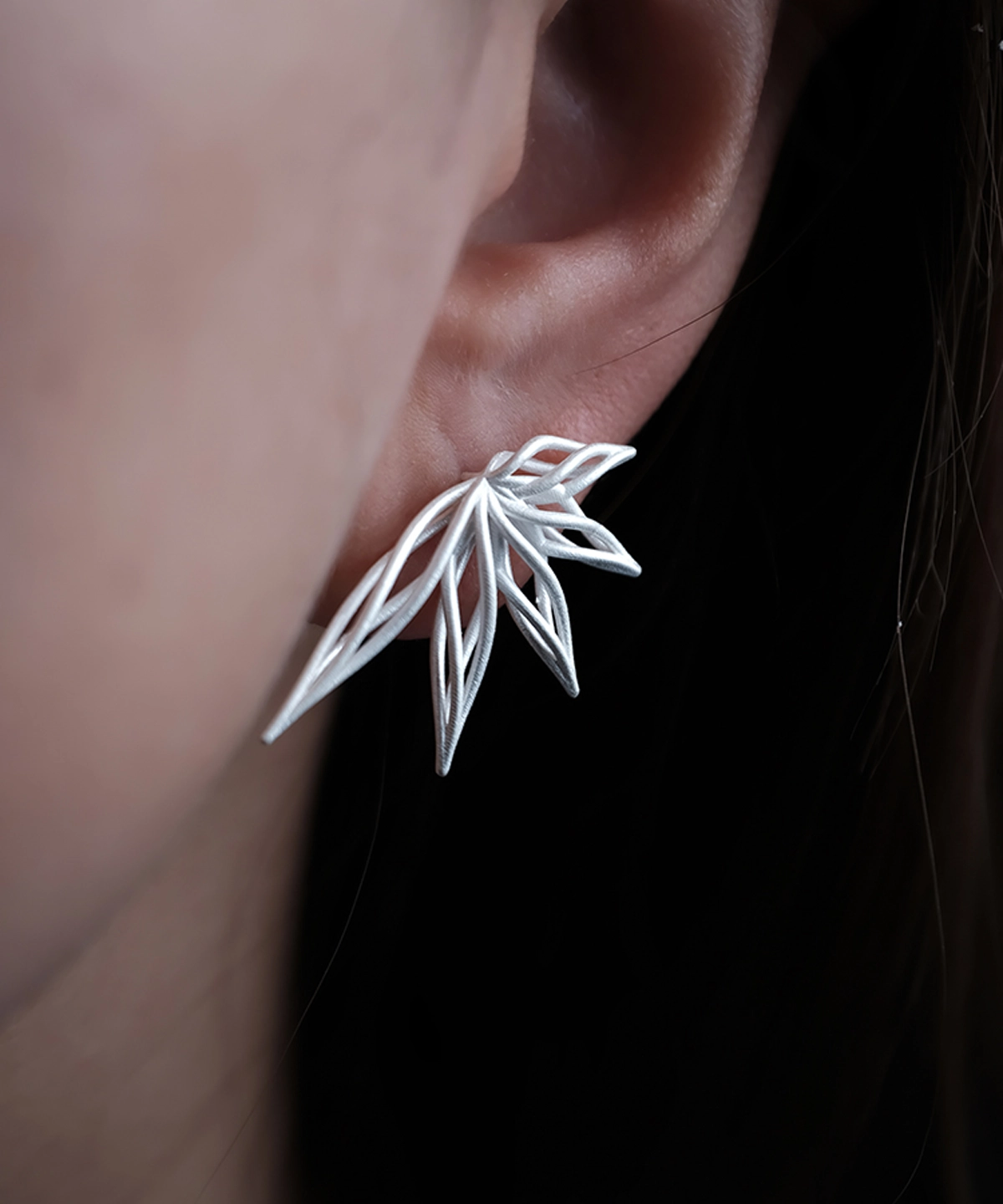 Close-up of an ear adorned with Dancing Petals-Organic Sterling Silver Statement Earrings, showcasing delicate petal-like silverwork.
