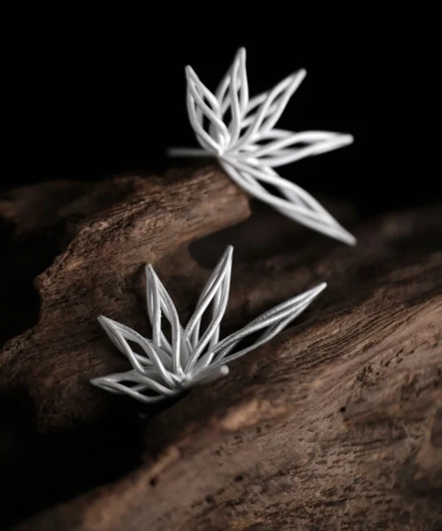 Organic sterling silver statement earrings featuring a flowing petal-inspired design, elegantly displayed on a rustic wooden surface.